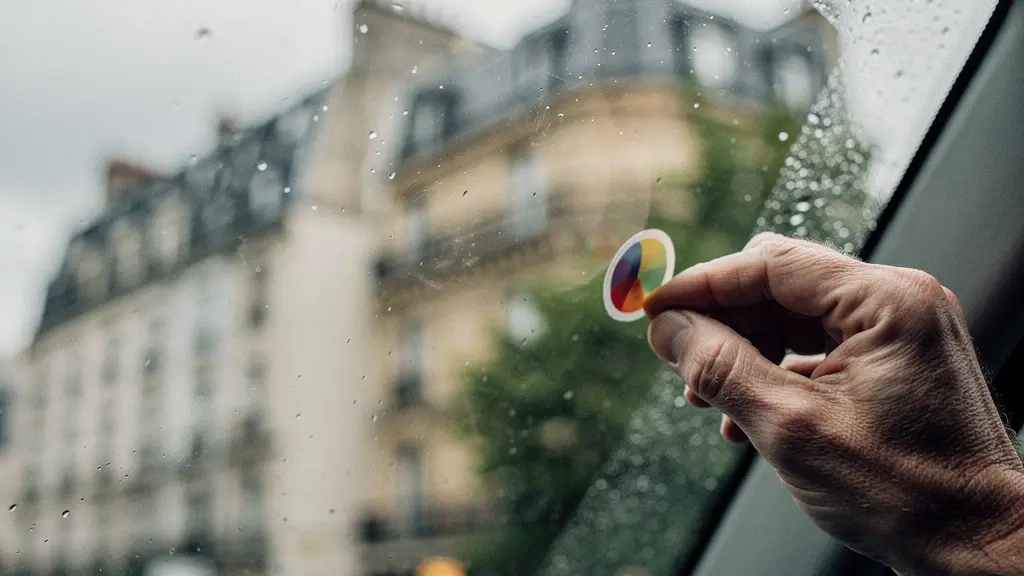 Détail d'un angle de pare-brise de voiture avec reflets de lumière urbaine et gouttes de pluie